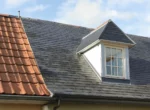 Toiture de maison avec ardoises naturelles, tuiles en terre cuite et lucarne en zinc