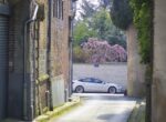 Voiture électrique blanche garée au bout d'une ruelle entre des murs de brique