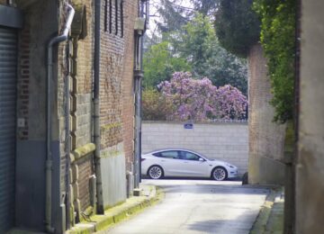 Voiture électrique blanche garée au bout d'une ruelle entre des murs de brique