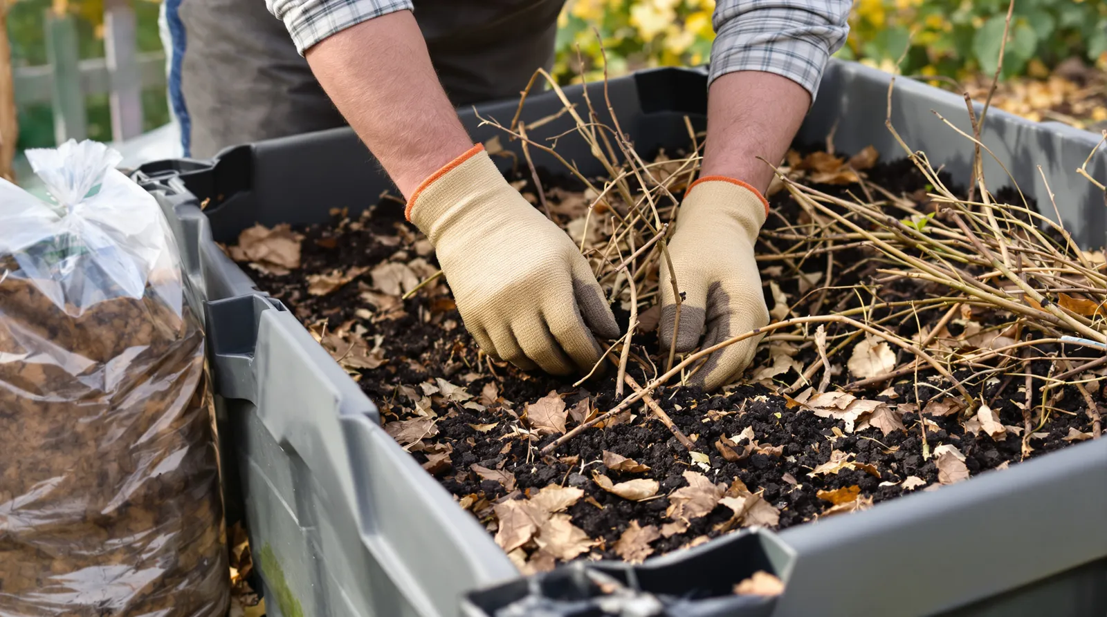 Remplissage en couches d'un bac potager avec branches, feuilles mortes et compost