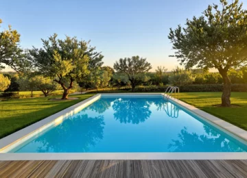 Piscine enterrée rectangulaire à l'eau turquoise dans un jardin au crépuscule